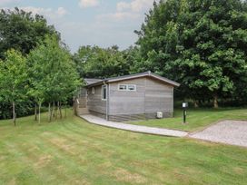 A wooden cabin surrounded by grass and trees at 24 Meadow Retreat Dobwalls