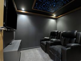 A home theater with black recliner chairs and a television at 24 Meadow Retreat Dobwalls