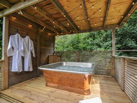 An outdoor spa area with a hot tub and robes at 24 Meadow Retreat in Dobwalls