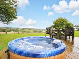 A hot tub on a wooden deck with a table and chairs at 8 Horizon View in Dobwalls