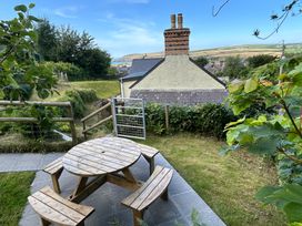 A garden with a wooden table and benches at Delfryn, Newport