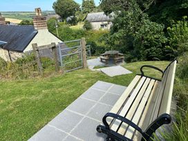 A garden with a bench, table, and chairs at Delfryn, Newport