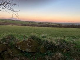 A rural landscape with green fields and a stone wall in the foreground at Y Gweithdy Rhos Eirin in Maenclochog