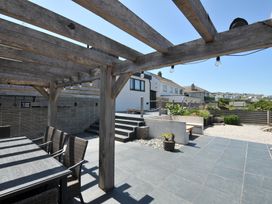 A garden with a wooden pergola and dining table at Breakers View in Polzeath