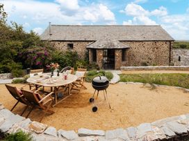 An outdoor dining area with a table and chairs at Hoppers Barn in Pancrasweek near Holsworthy