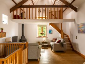 A living room with a staircase and window at Hoppers Barn Pancrasweek near Holsworthy