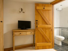 A bathroom with a television and wooden furniture at Hoppers Barn Pancrasweek near Holsworthy