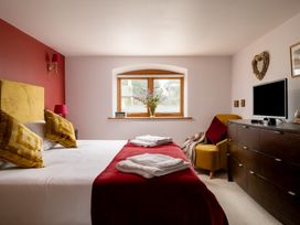 A bedroom with a bed, dresser, and window at Hoppers Barn in Pancrasweek near Holsworthy