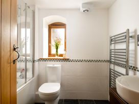 A bathroom with a shower, toilet, sink and window at Hoppers Barn in Pancrasweek near Holsworthy