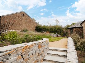 A garden with a stone wall and gravel path at Hoppers Barn Pancrasweek near Holsworthy