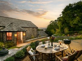 An outdoor dining area with a table and chairs at Hoppers Barn Pancrasweek near Holsworthy