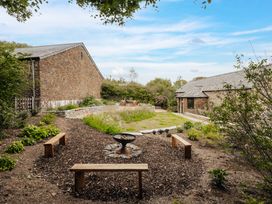 A garden with a fire pit and wooden benches at Hoppers Barn Pancrasweek near Holsworthy