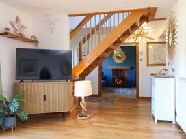 A living room with a television on a stand and a staircase at Hillsview in Combe Martin