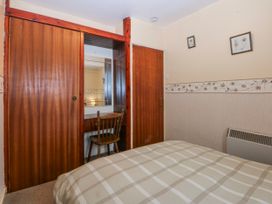 A bedroom with a bed, chair and mirror at First Floor Apartment in Tremadog