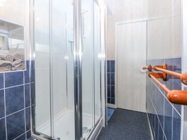 A bathroom with a shower and towels at First Floor Apartment in Tremadog
