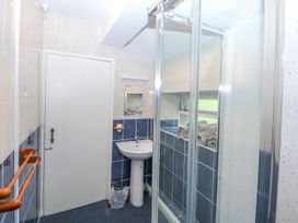 A bathroom with a shower, sink, and towels at First Floor Apartment in Tremadog
