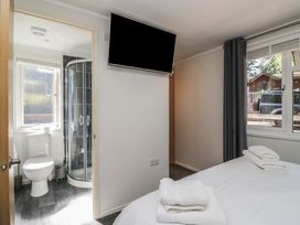 A bedroom with a bed and attached bathroom at Treetops, Beech Hill 13, Fallbarrow Park near Bowness-On-Windermere