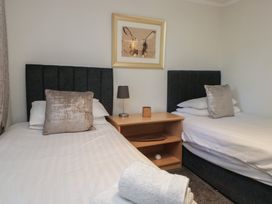 A bedroom with two beds and a bedside table at Treetops Beech Hill 13 ,Fallbarrow Park near Bowness-On-Windermere