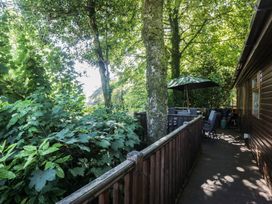 An outdoor area with a table and chairs under an umbrella at Treetops Beech Hill 13, Fallbarrow Park near Bowness-On-Windermere