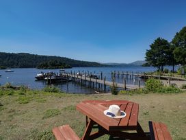 A picnic table with a hat and sunglasses near the water at Treetops Beech Hill 13 ,Fallbarrow Park near Bowness-On-Windermere