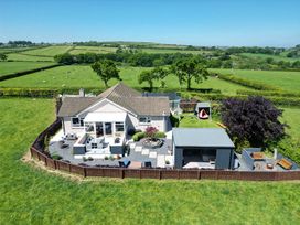 An aerial view of a fenced house with patios play area and garden furniture in the countryside at Ashlea Launceston