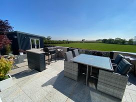 An outdoor patio with a table and chairs a barbecue grill raised counter and a small building with glass doors overlooking a grassy field at Ashlea in Launceston