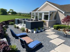 A garden patio with blue cushioned loungers a stone table and a raised dining area outside a house at Ashlea in Launceston