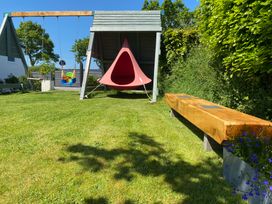 A garden with a children's swing, a hanging chair, a wooden bench, and green grass at Ashlea in Launceston