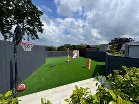 A backyard with artificial grass basketball hoop children's slide and swing set at Ashlea in Launceston
