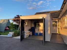 An open garage with hangers and containers next to a garden with a wooden play structure at Ashlea in Launceston