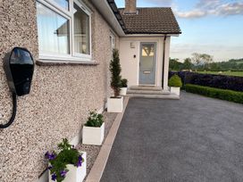 A house entrance with potted plants along the wall and a gray door at Ashlea in Launceston