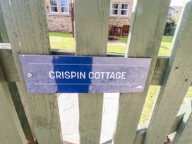 A sign for Crispin Cottage on a green gate at Crispin in Lucker