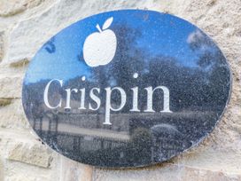 A sign with the name Crispin and an apple icon on a stone wall