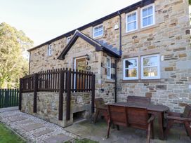 An outdoor seating area with a stone house and wooden furniture at Pippin in Lucker