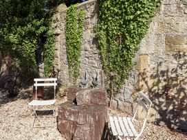 A garden area with a stone wall and wooden table at Pippin in Lucker