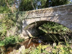 A stone bridge over a stream surrounded by trees at Pippin in Lucker