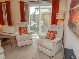 A living room with armchairs and a sliding door at Ahoy in Seahouses