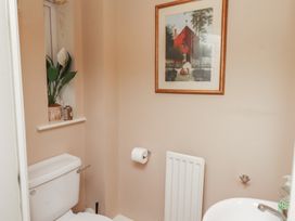 A bathroom with a toilet, wash basin, and wall art at Ahoy, Seahouses