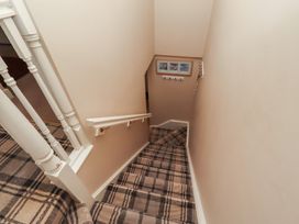A staircase with a handrail and pictures in the stairway at Ahoy in Seahouses