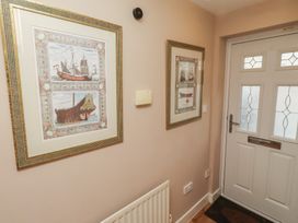 A hallway with framed maritime art and a door at Ahoy in Seahouses