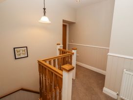 A hallway with a staircase and light fixture at Bramley in Lucker