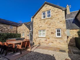 An outdoor area with a stone house and seating at Bramley in Lucker