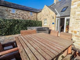 A dining area with a hot tub and wooden furniture at Bramley in Lucker