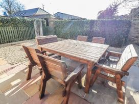 A garden with a wooden table and chairs at Bramley in Lucker