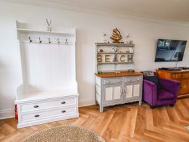 A living room with a coat rack and sideboard at Farne Cottage Beadnell