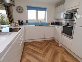 A kitchen with white cabinets and appliances at Farne Cottage Beadnell