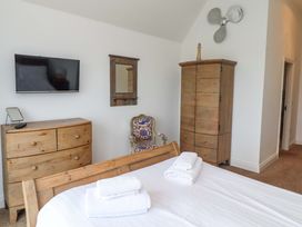 A bedroom with furniture and a television at Farne Cottage Beadnell