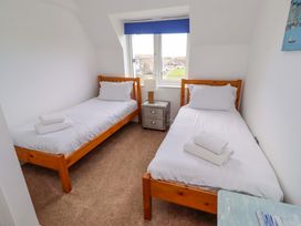 A bedroom with two single beds and a nightstand at Farne Cottage in Beadnell