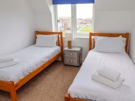 A bedroom with two beds and a lamp at Farne Cottage in Beadnell