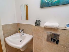 A bathroom featuring a sink, mirror, towel and a toilet flush at Farne Cottage Beadnell